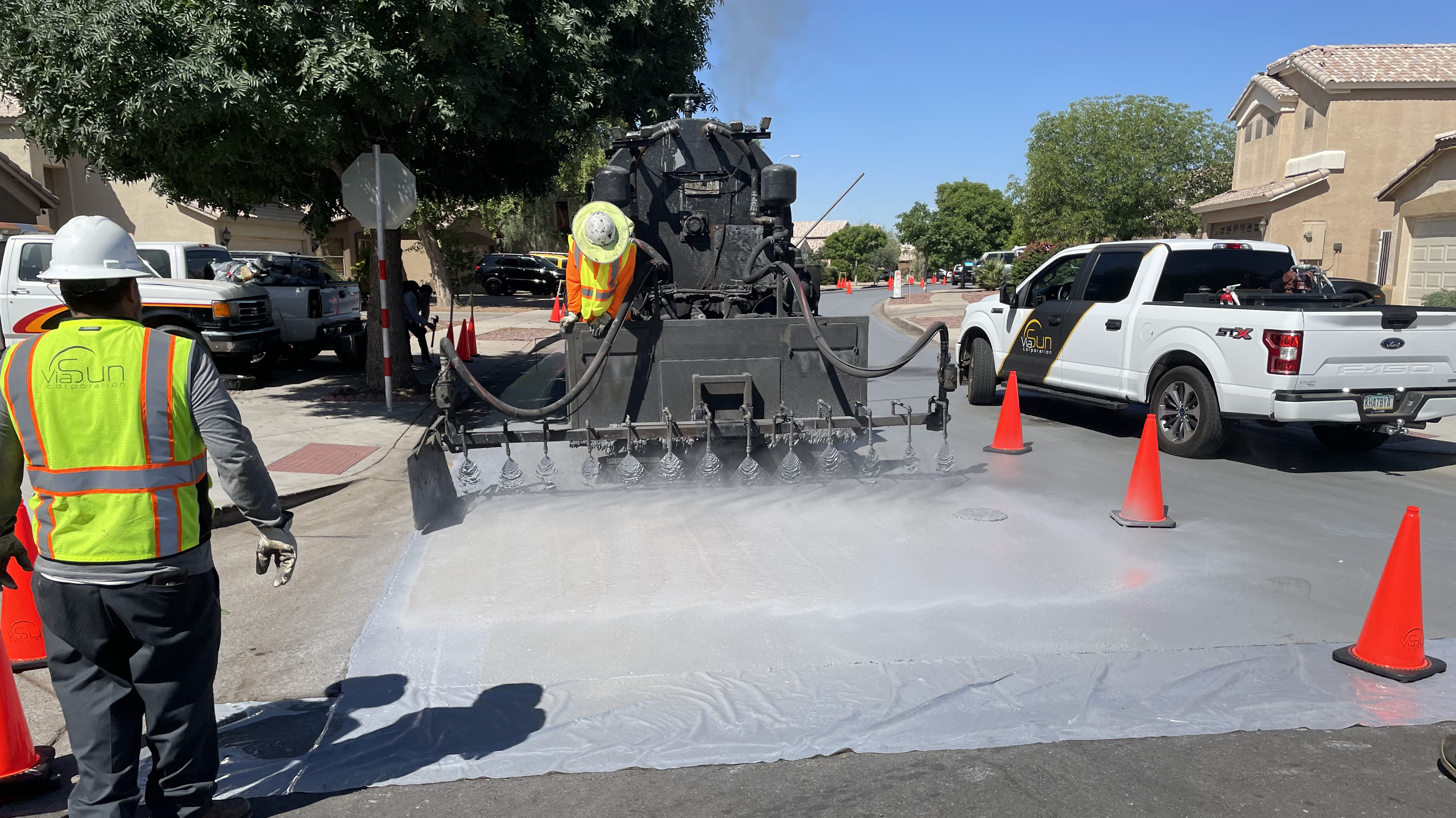 A work crew applies sealant to a neighborhood street